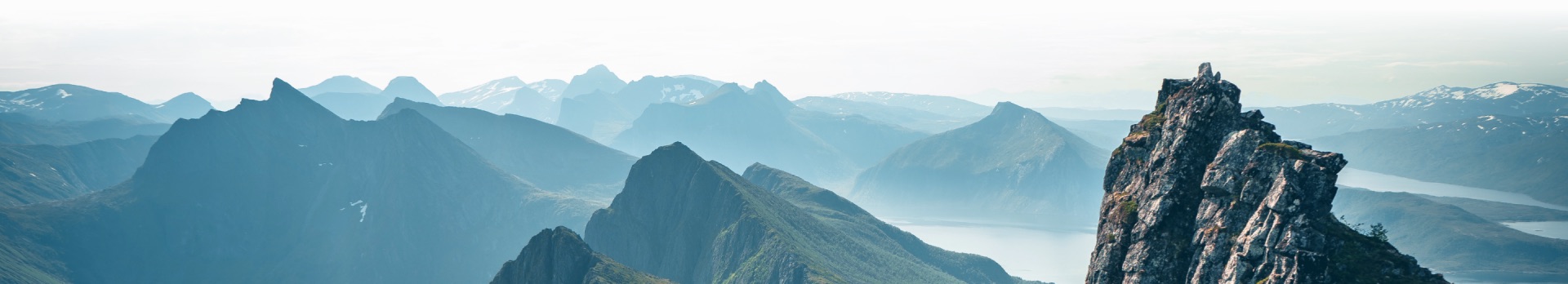 Ampio paesaggio montano al crepuscolo, vette e valli in toni di terra tenui
